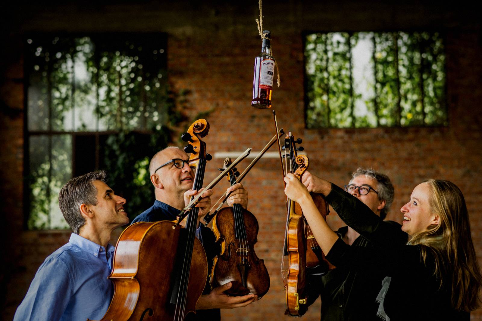 Le Bowmore Quartet lève ses instruments sous une bouteille de whisky Bowmore suspendue